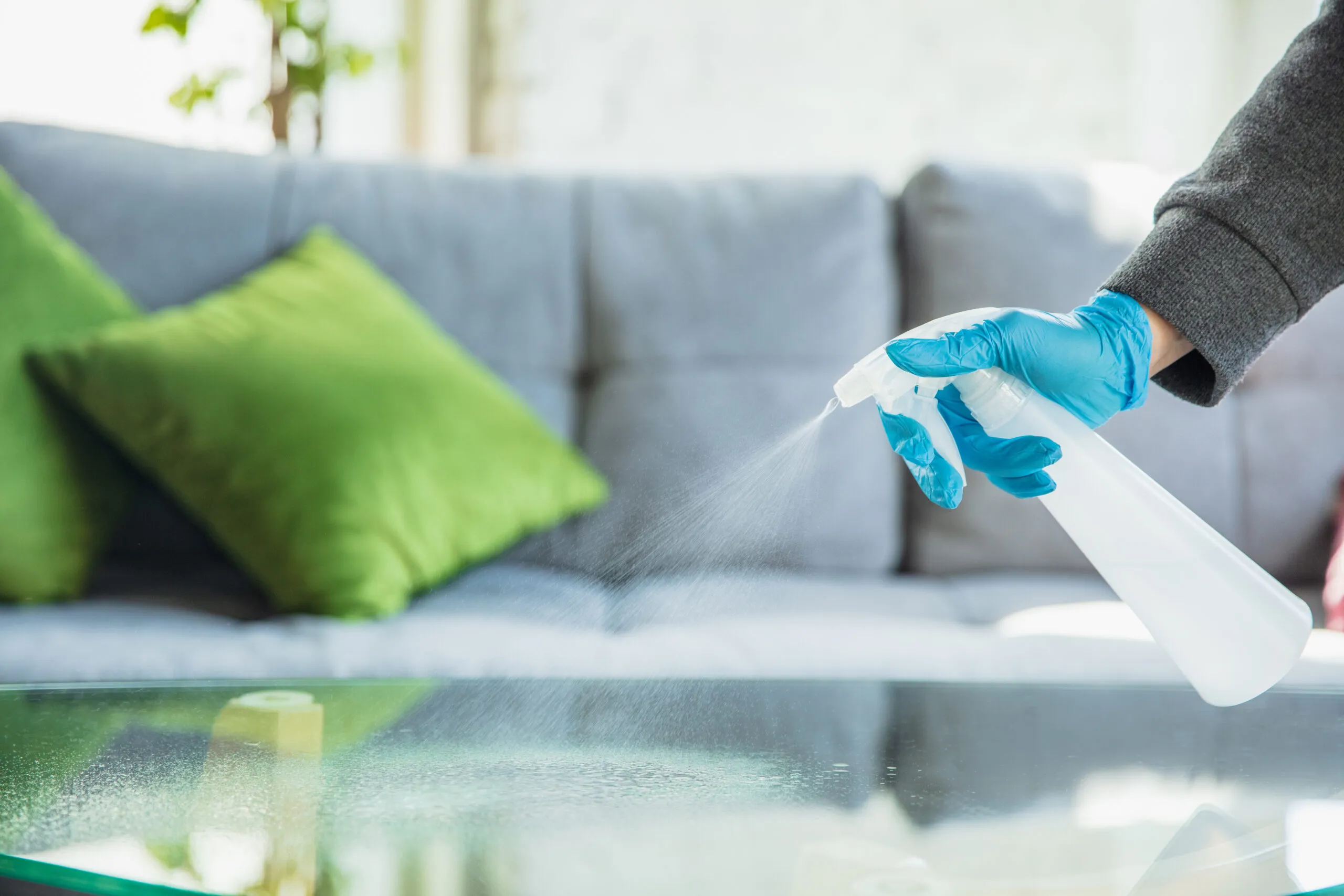 Hand in gloves cleaning table at home.