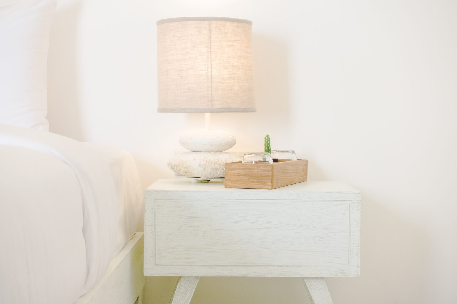 White bedside table with a white lamp.
