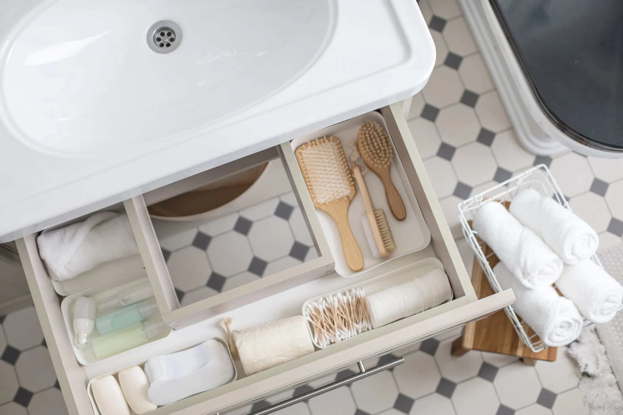 Bathroom cabinet organizers, Marie Kondo's method organization of bathroom amenities in modern open shelf case.