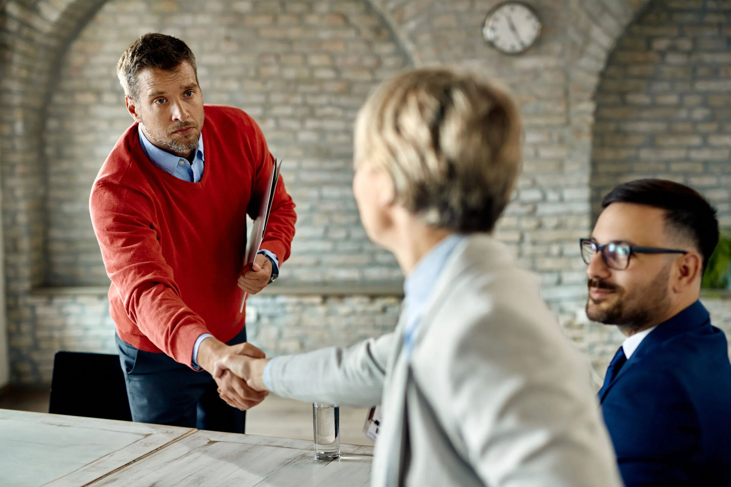 Mid adult businessman shaking hands with colleagues while having a meeting in the office.