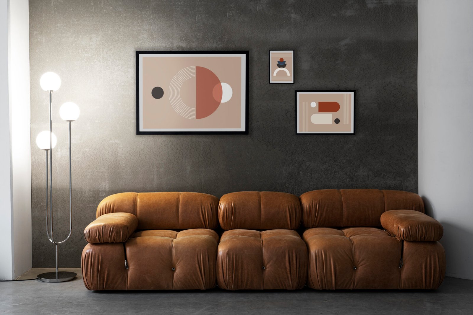Brown leather couch with concrete wall and abstract art. 