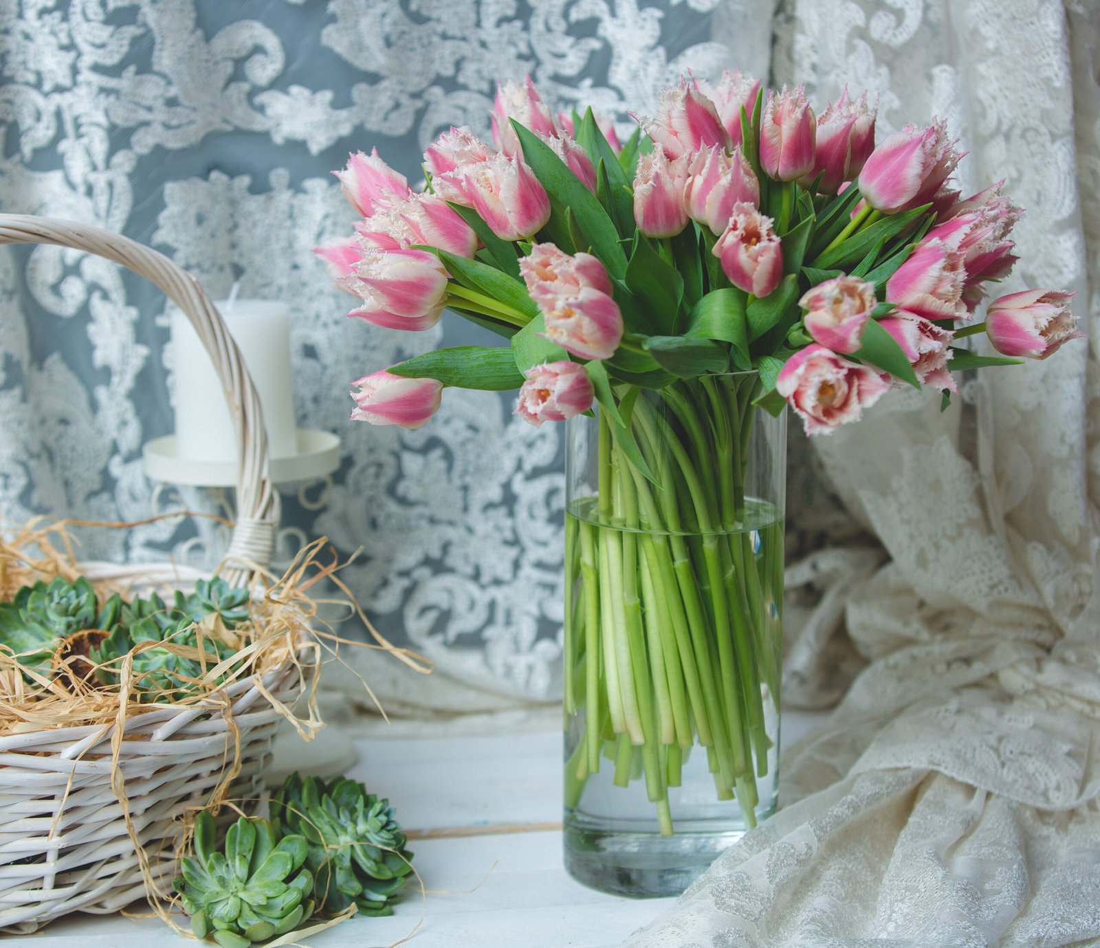 Tulips in a vase on a white wooden table. 