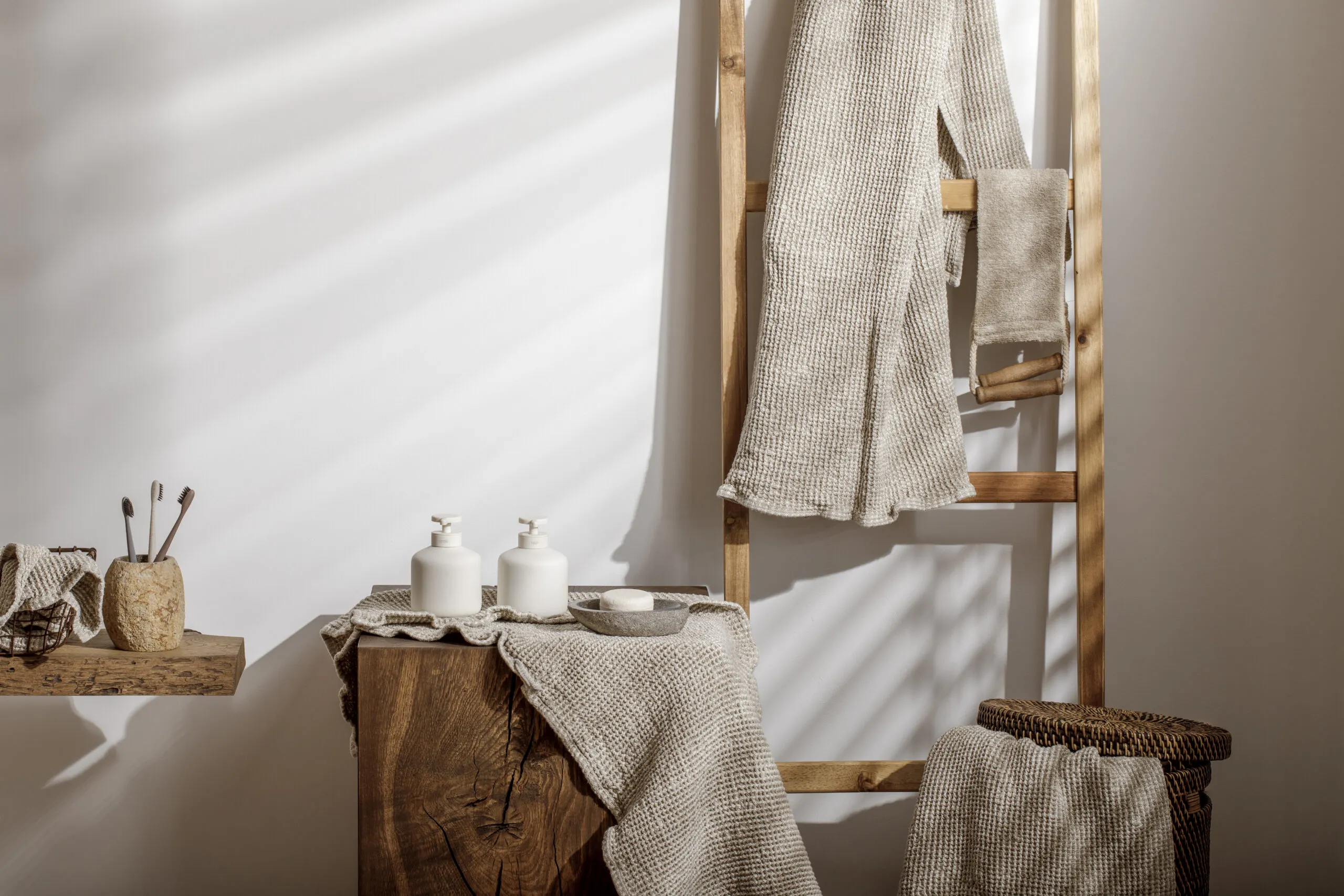 Organic waffle linen towels, bathroom zero waste accessories on solid oak stump in modern bathroom interior.