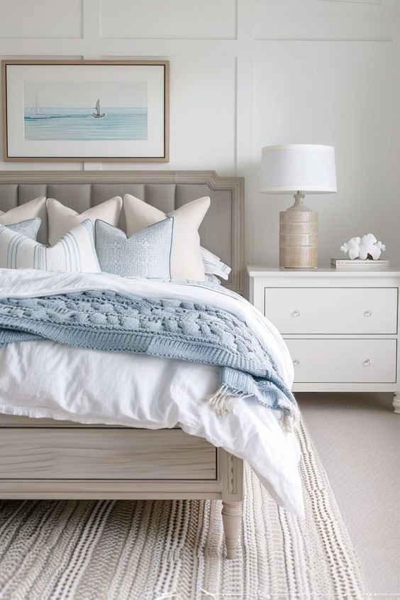 Coastal bedroom with a wooden bedframe, wooden bedside table and ocean blue details. 