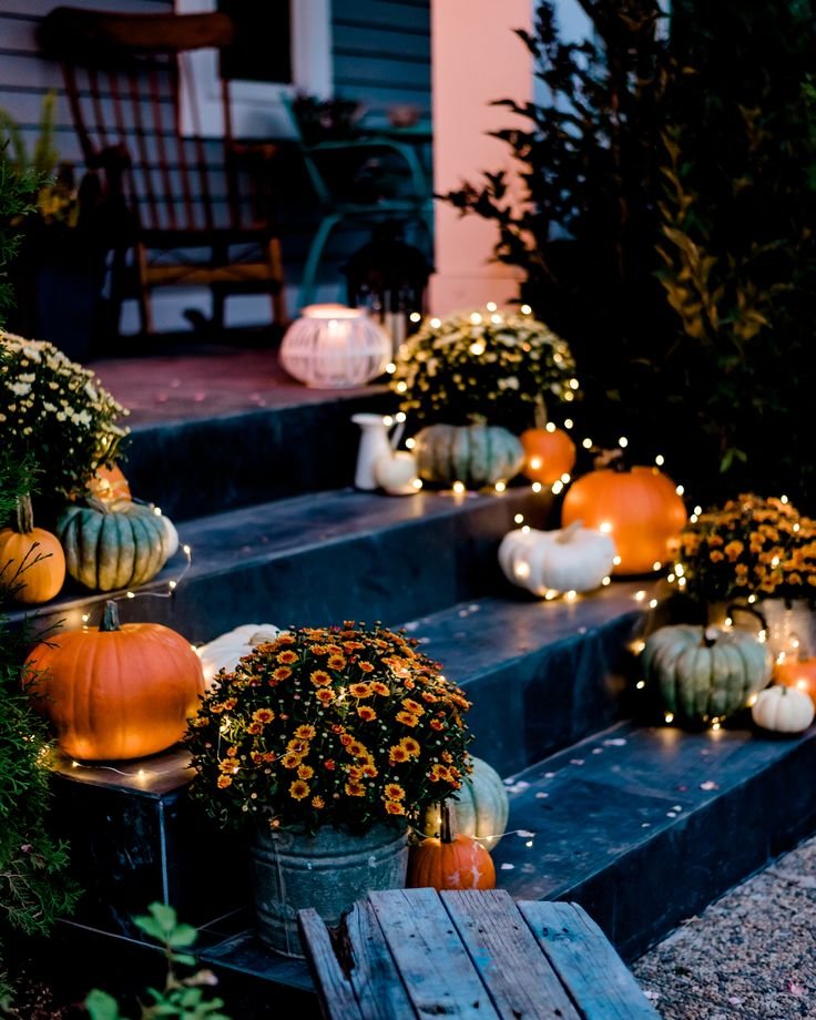 front porch with mums in pots and pumpkins.