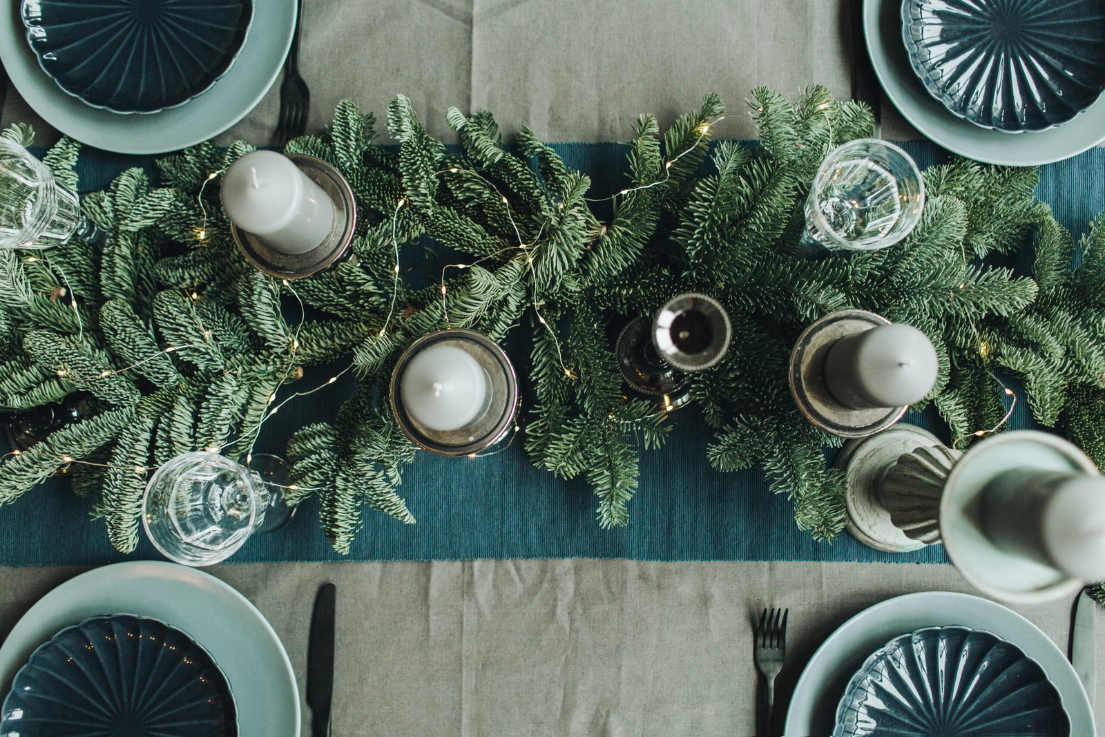 Christmas composition. Festive christmas table decorated with fir branches, garland, candles, plates, knifes, forks. How To Decorate A Dining Room Table For Christmas. 