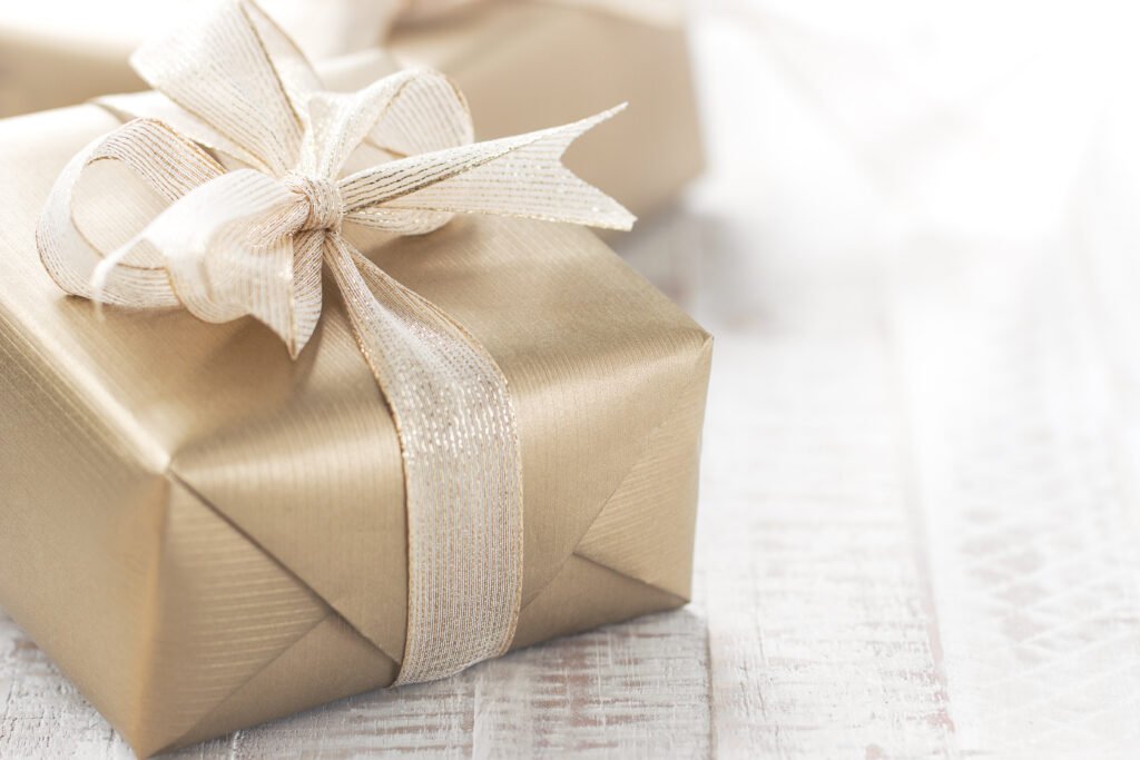 Golden gift boxes with beautiful ribbon and bow on a bright shiny background.