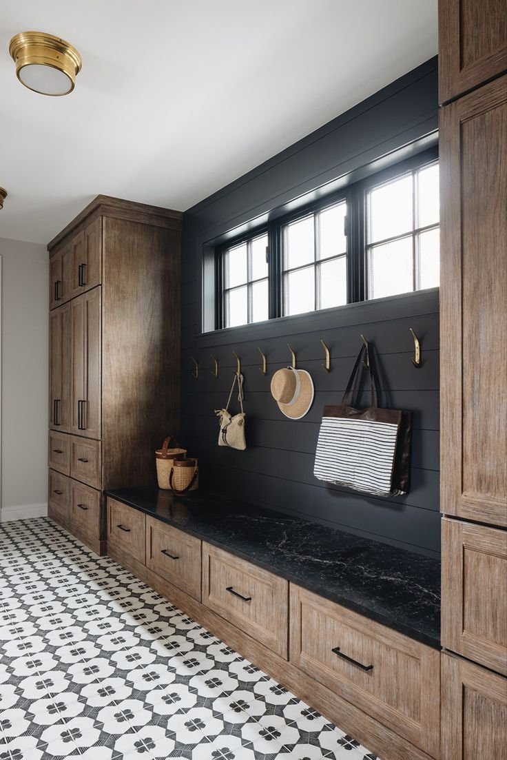 Elegant wooden and black mud room with patterned floor. 