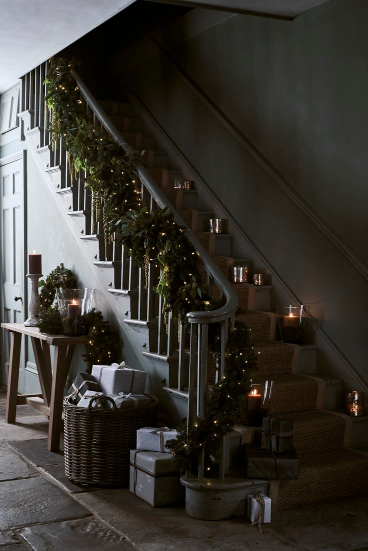 Moody hallway with a green garland and candles on the stairs. 