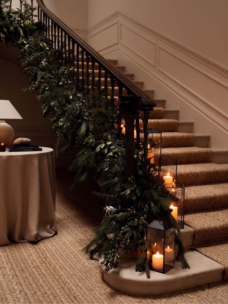 Christmas decorated hallway with green garland and candles on the stairs. 