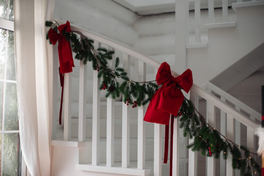 Christmas Hallway Decorating Ideas with red bows and a garland.