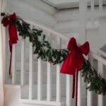 Christmas Hallway Decorating Ideas with red bows and a garland.