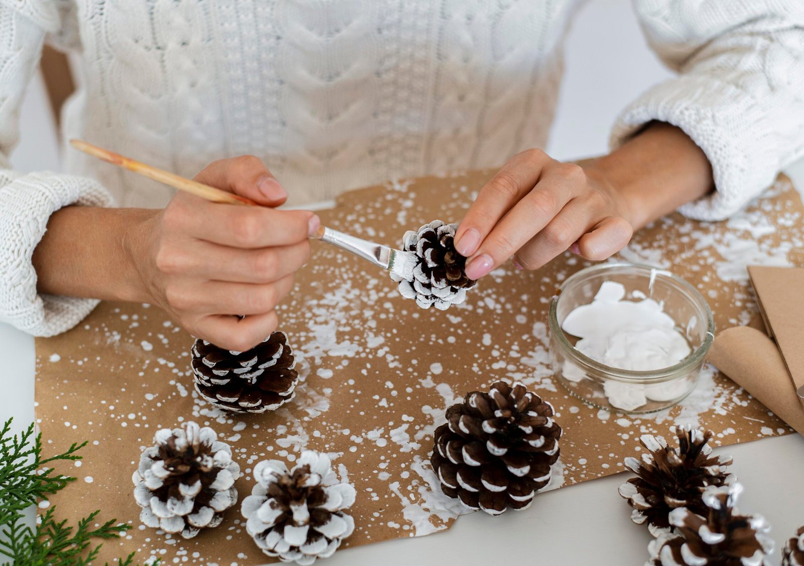 High angle person painting pinecones for DIY Christmas decor. 