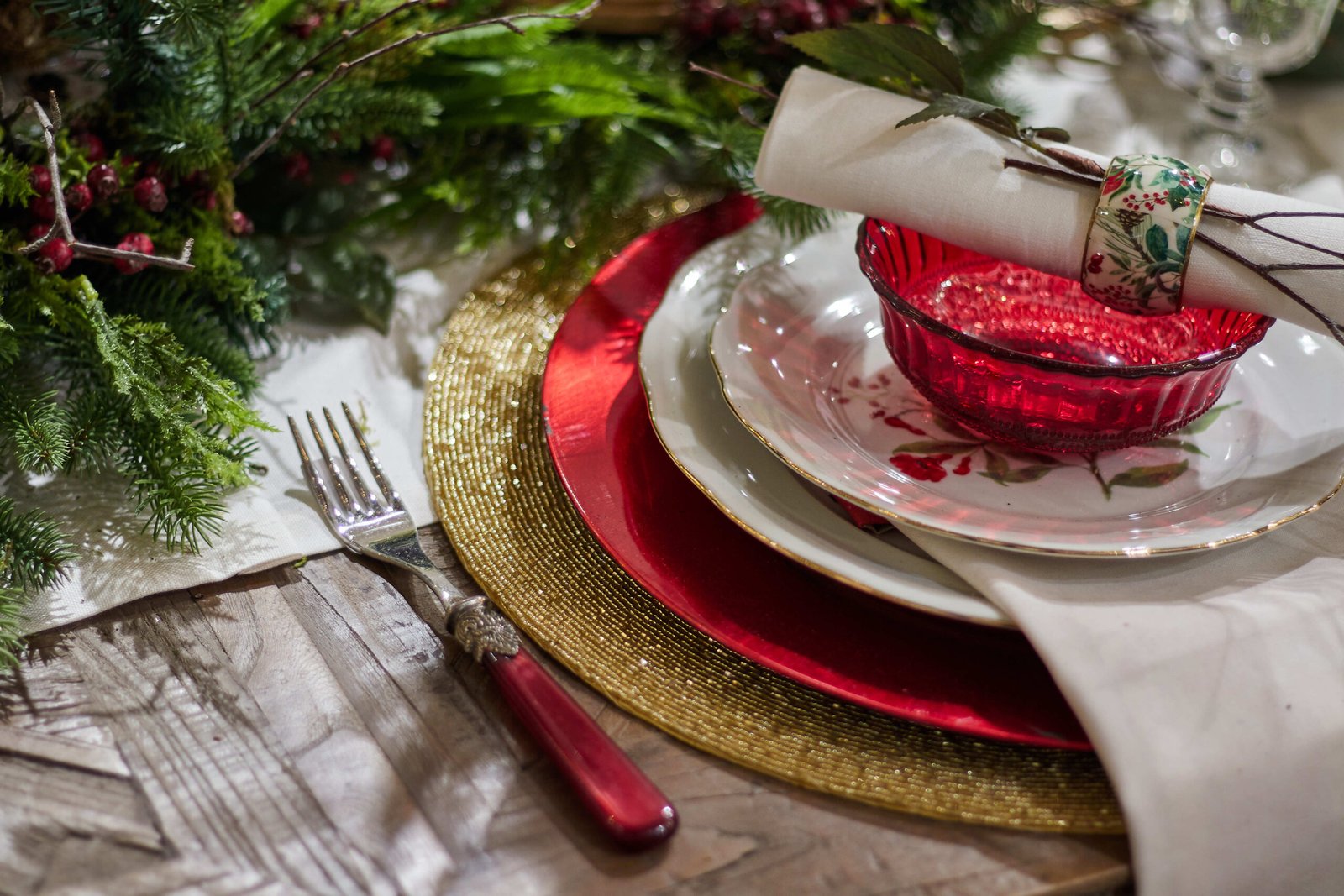 A high angle shot of Christmas dinner set up with glasses and ornaments on a table.