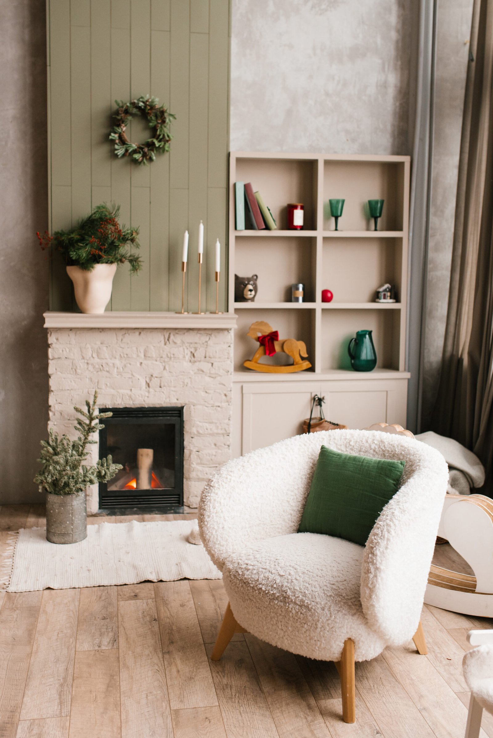 Cozy living room with a fireplace, a white chair, and a green pillow. Warm and inviting atmosphere, perfect for relaxing and spending time with family and friends