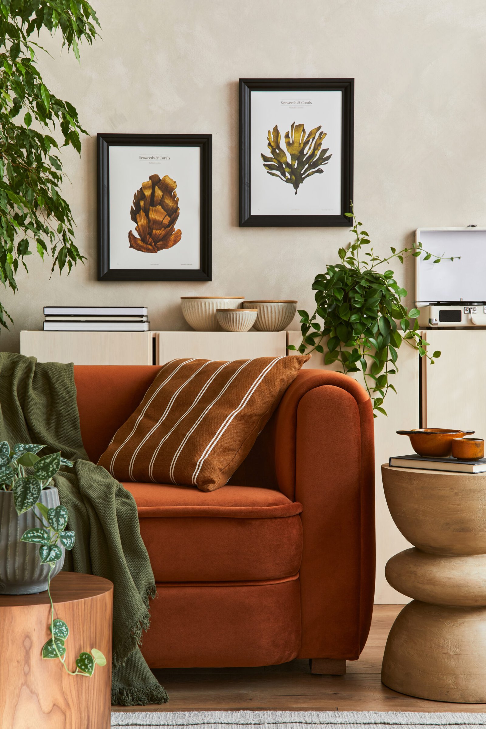 Creative interior composition of living room with designed couch, two mock up poster frames, coffee table, palnts, books and personal accessoriers.