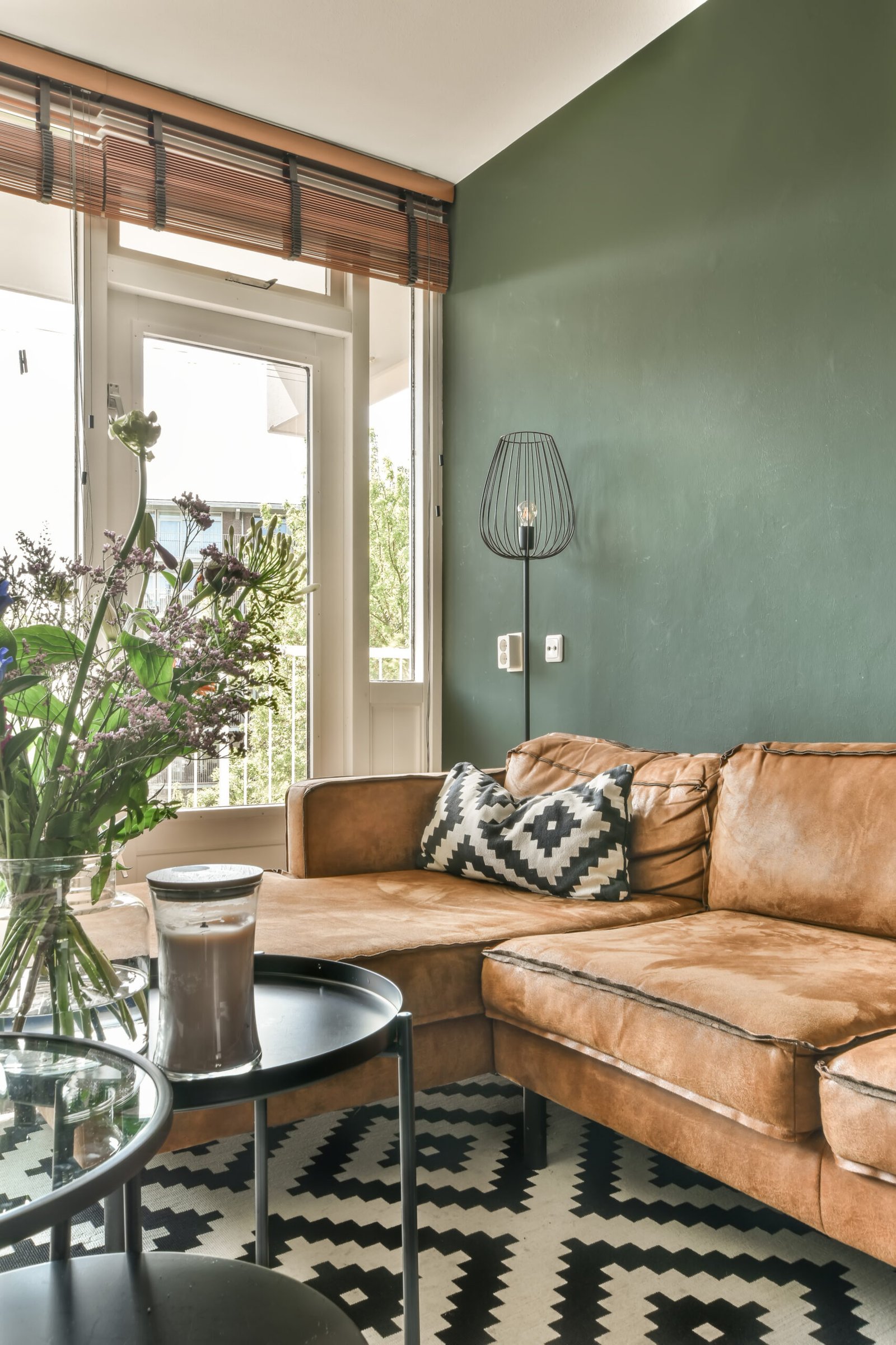 a living room with a brown leather couch and black and white patterned rug on the floor next to a glass coffee table