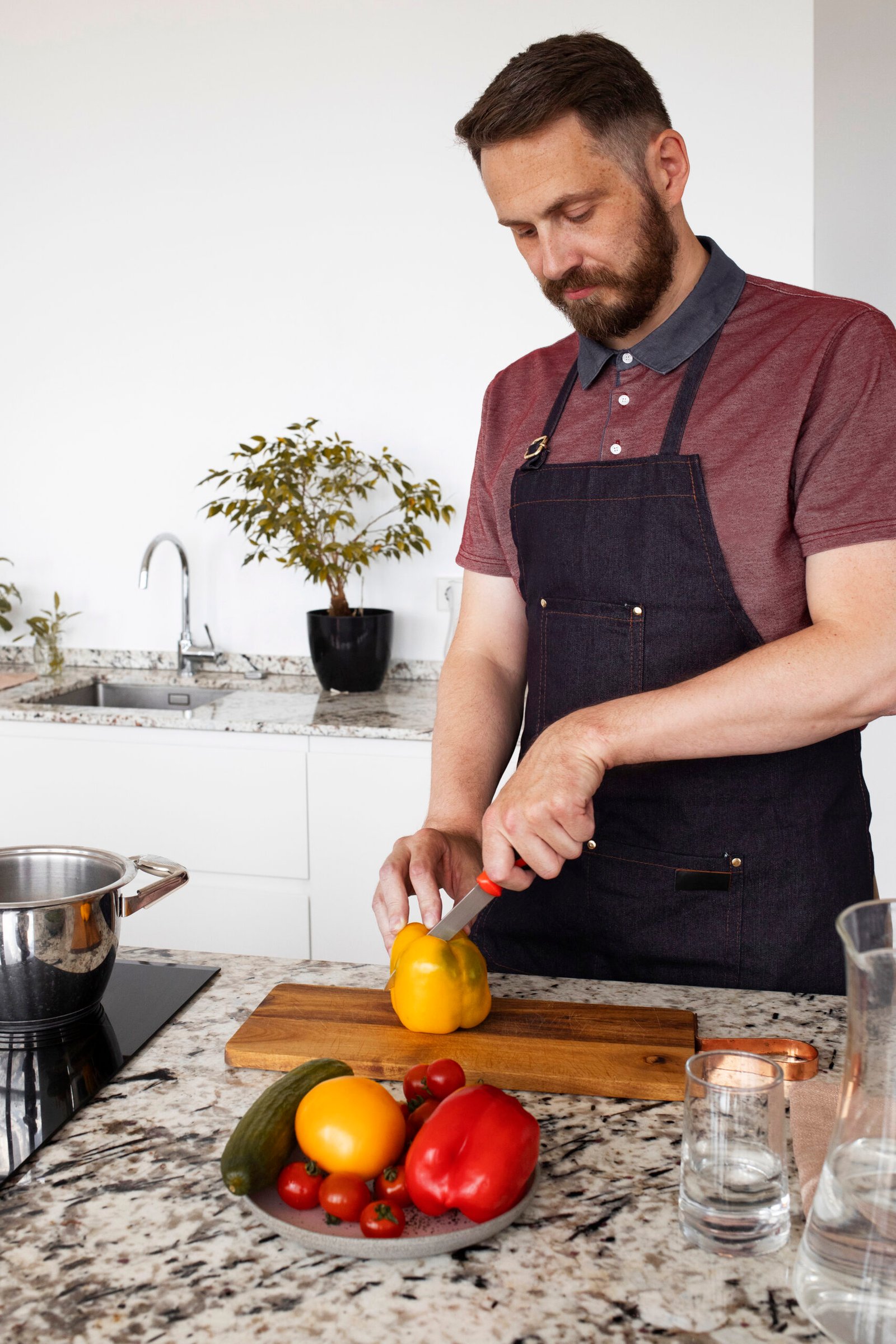 Man cutting paprika on a wooden cutting board in a kitchen. 