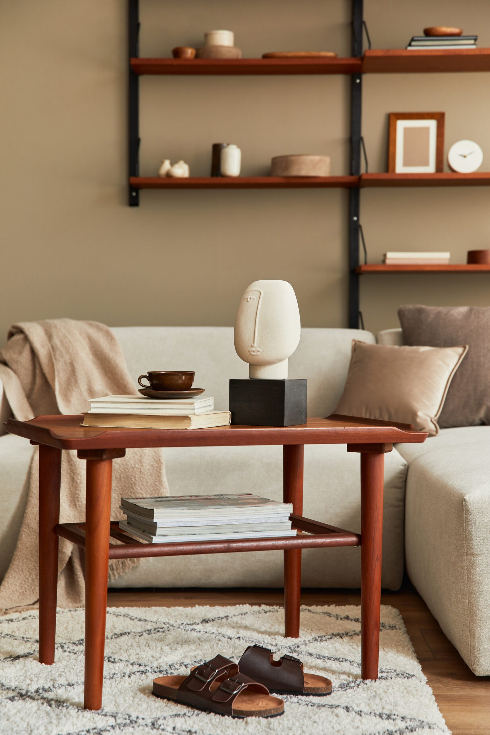 Stylish interior of living room with design wooden coffee table, beige sofa, cup of coffee, book, decoration and elegant accessories in stylish home decor. 