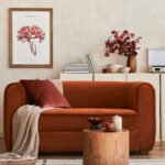 Stylish interior of modern living room with retro design sofa, mock up poster frame, pouf and creative personal accessories.