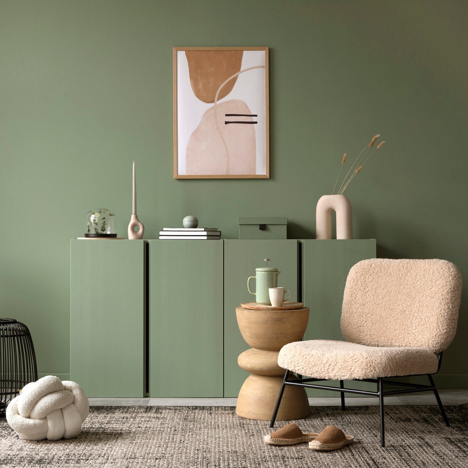 Stylish living room interior design with mock up poster frame, frotte armchair, wooden commode, side table, plants and creative home accessories. Sage green wall. 