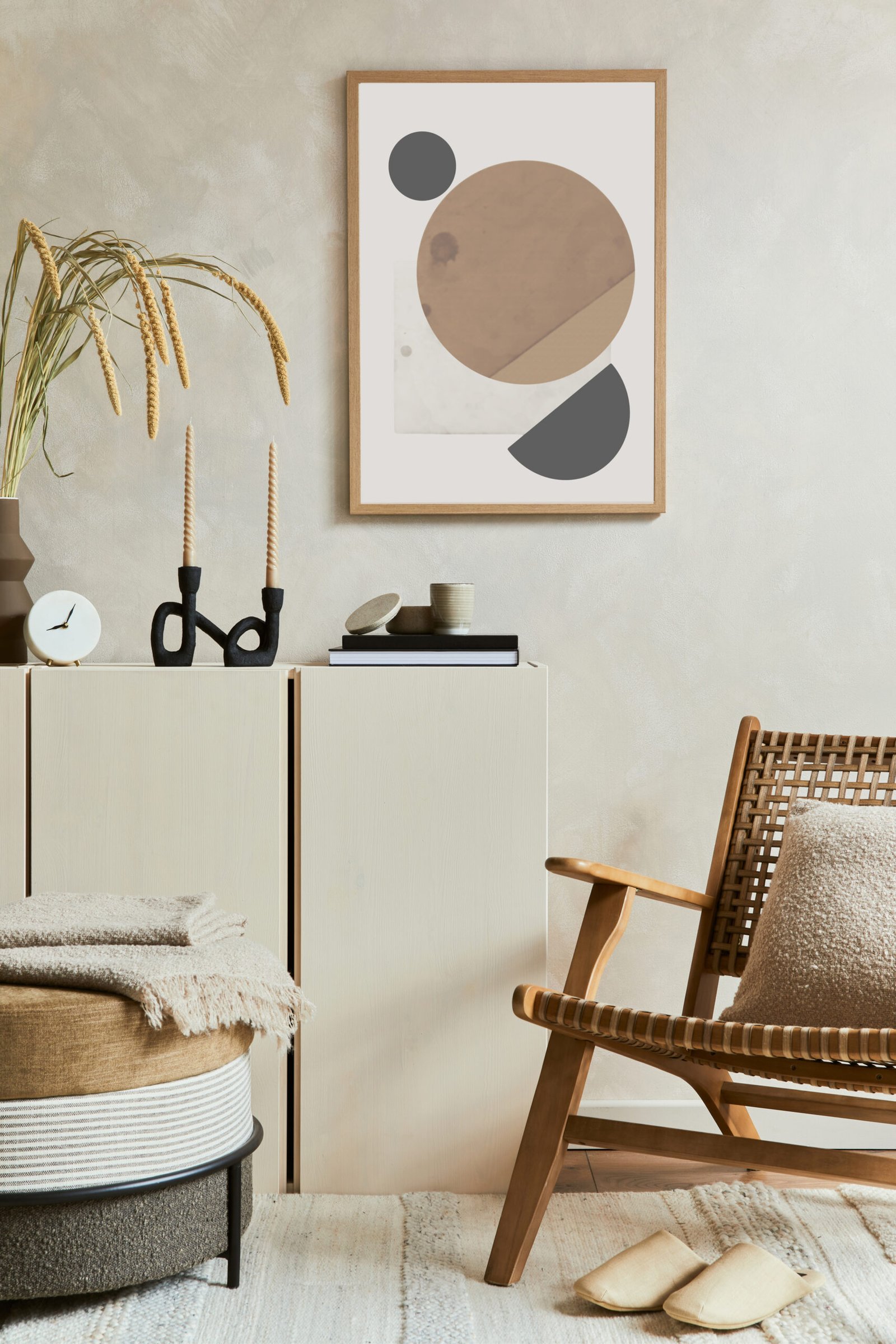 Stylish and modern beige living room interior composition with mock up poster frame, beige wooden sideboard, armchair and boho inspired accessories. 