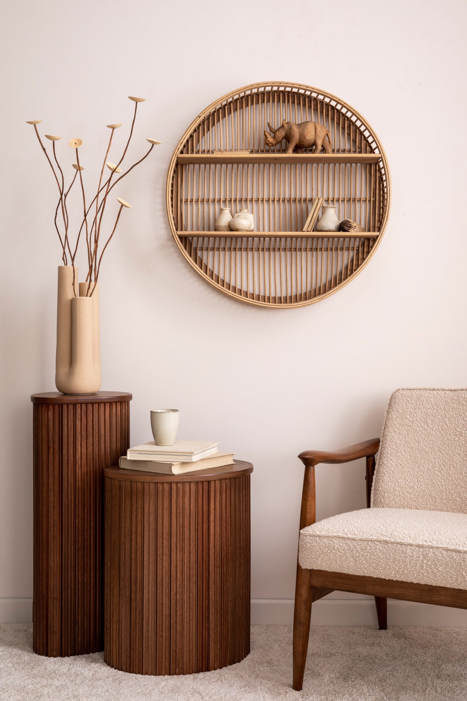 Warm and cozy composition of living room interior with round shelf , boucle armchair, elegant wooden stand, vase with dried flowers and stylish personal accessories. 