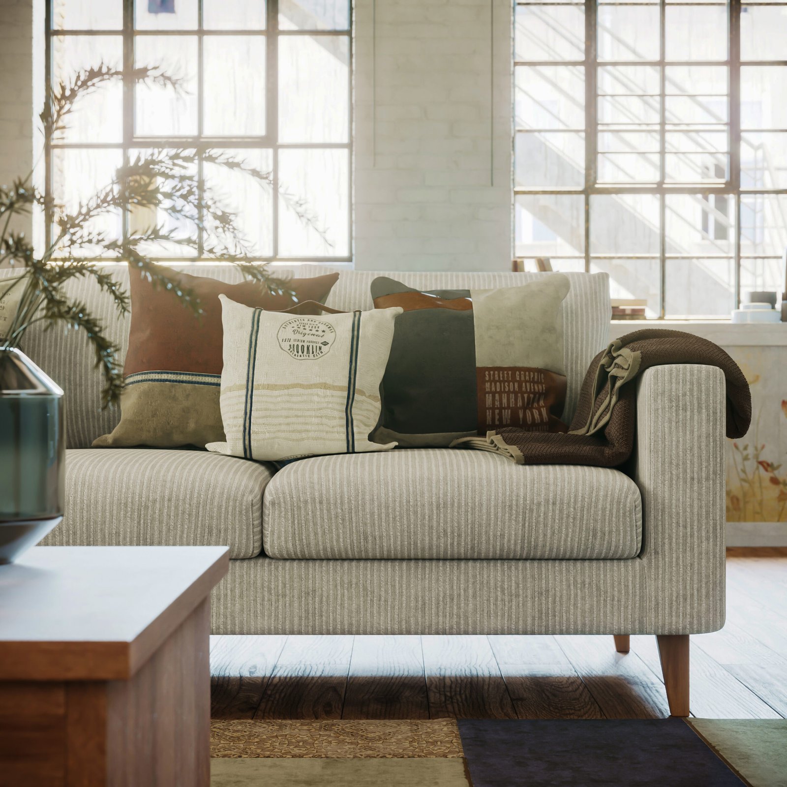 A beige neutral sofa with pillows with patterns on it. A wooden coffee table and large windows behind the sofa. 