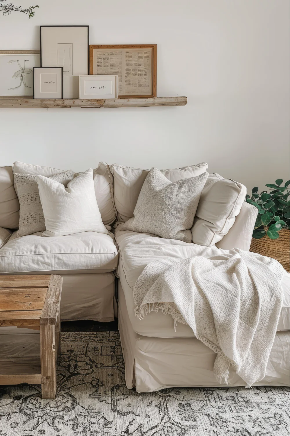 Cozy white couch with pillows and blanket in living room with window and picture on the wall