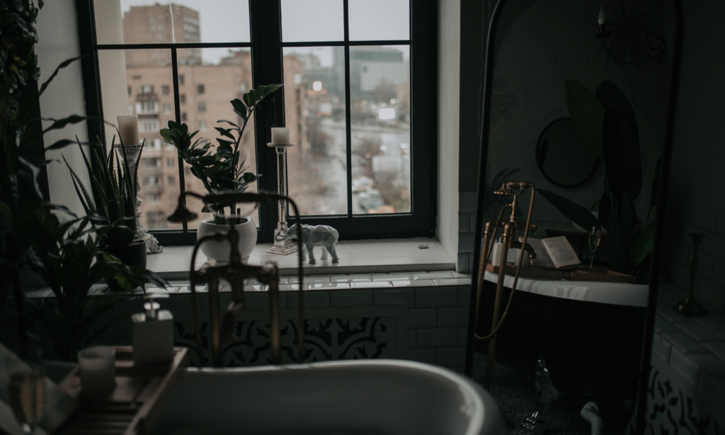 luxury interior bathroom with a large bathtub and natural light. Lots of plants.