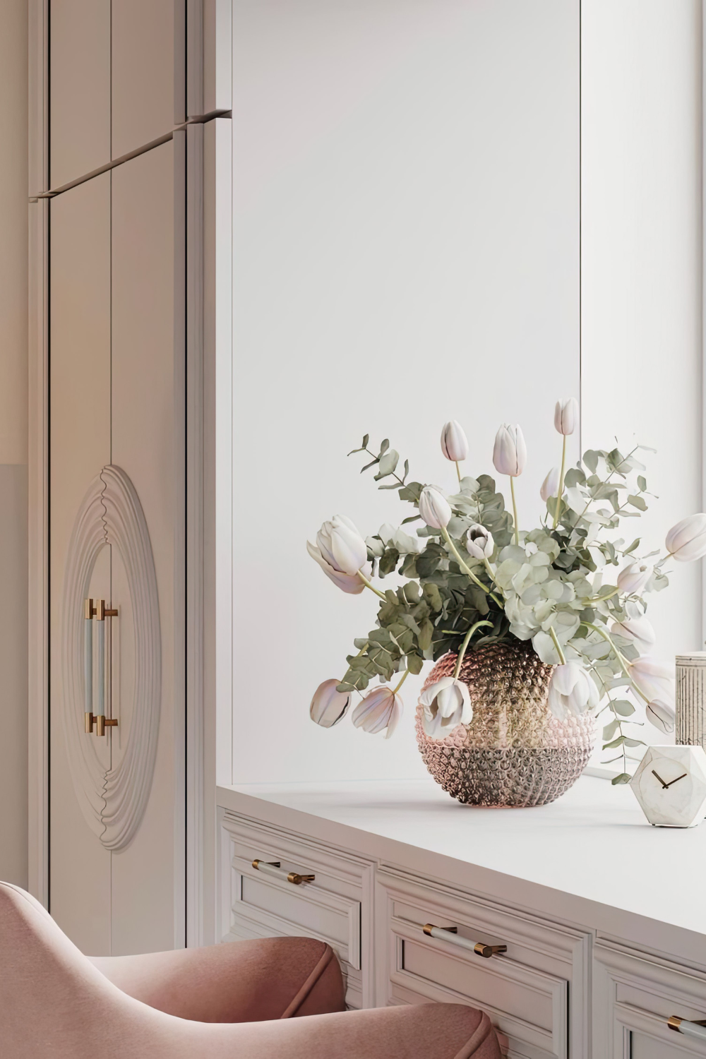 A pink chair, a neutral colored closet and a pink vase with flowers in it.