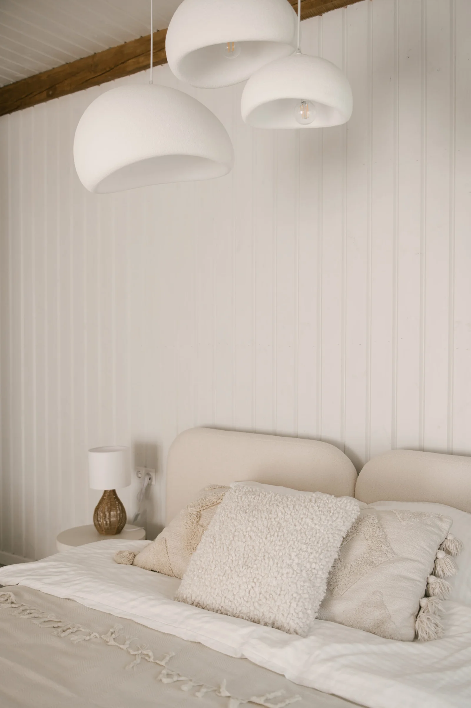 Beautiful light beige interior with soft white bed decorated with pillows in japandi and wawabi sabi style, cozy home concept