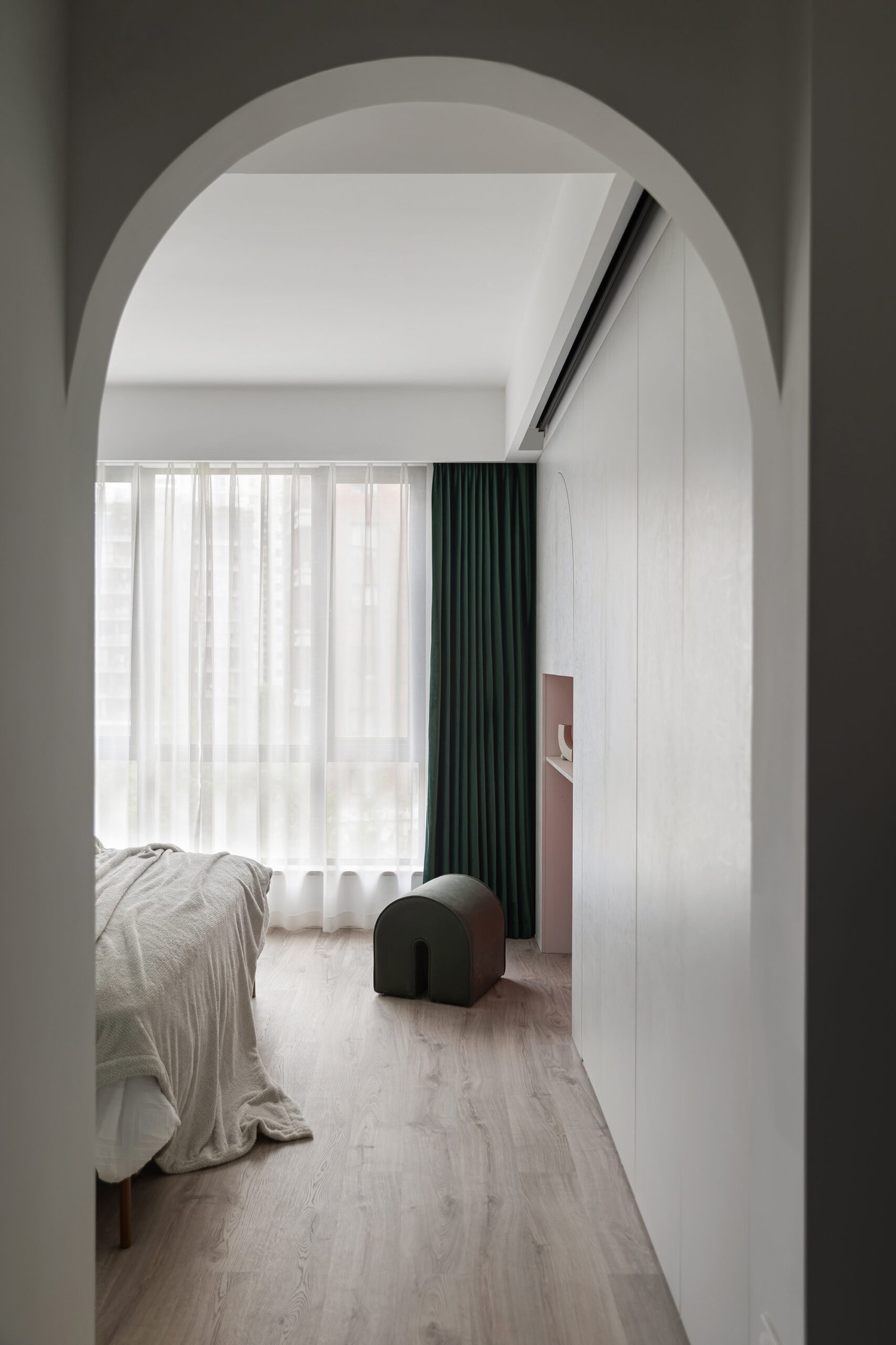 Bedroom with green curtain and an arched entry. 