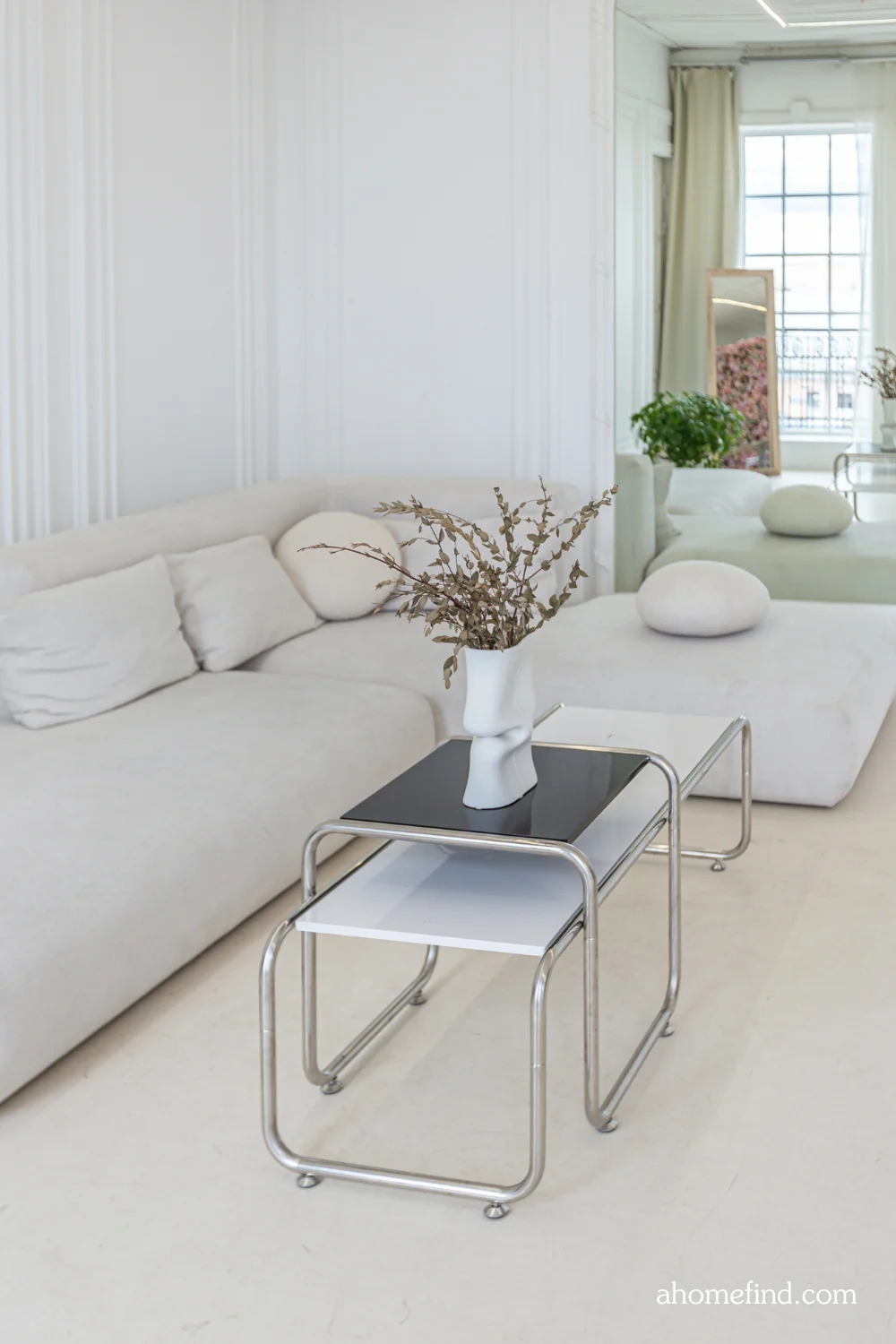 minimalist apartment decorating with a beige sofa, minimalist coffee table and a large floor mirror. 