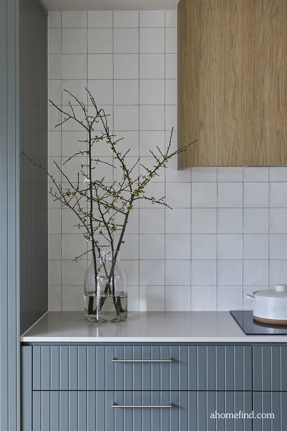 affordable small space decorating. a blue kitchen with a white counter top and white tiles on the walls. A clear vase. Scaled.