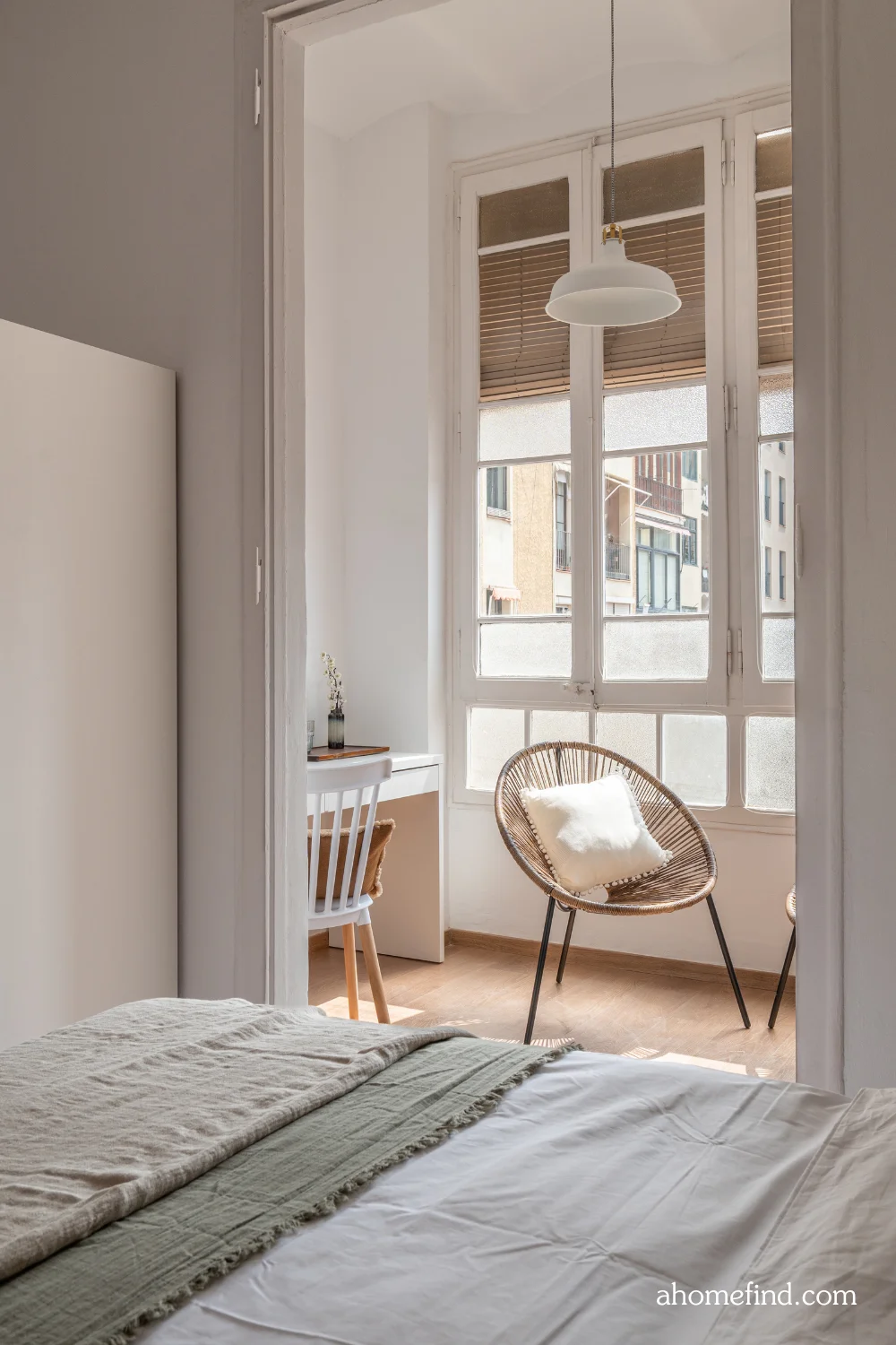 decorating a small apartment on a budget. A closeup on a bed and a chair in the background. A large window. Scaled. 