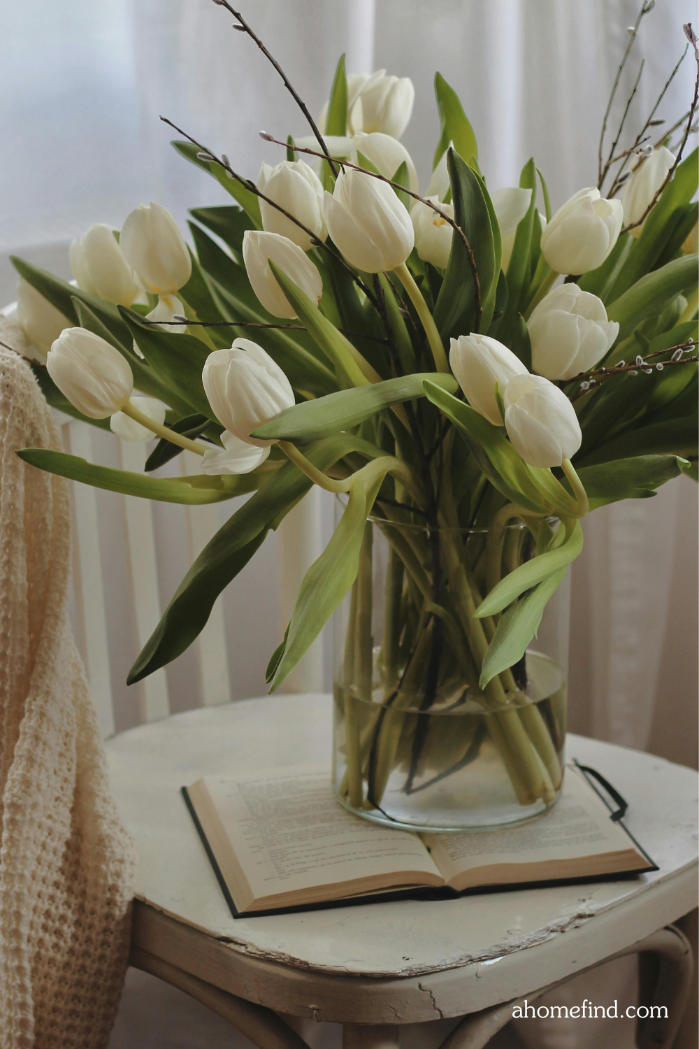 Spring home decor, tulips in a vase on a book on a chair. Spring dining room. Scaled. 