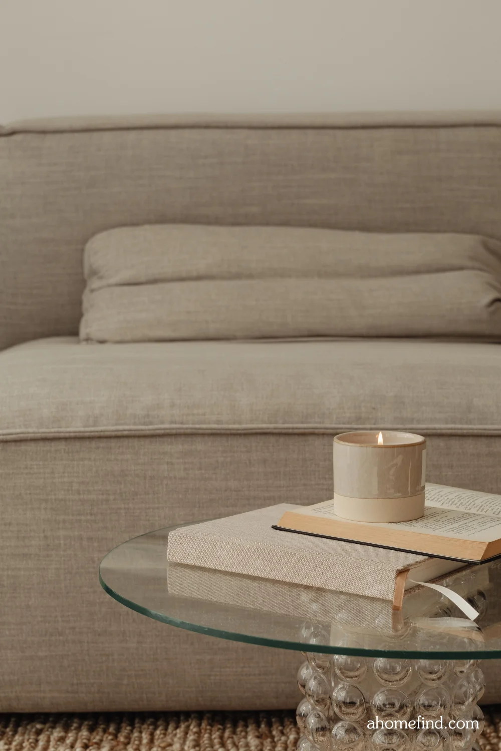 affordable small space decorating and minimalist apartment decorating. Closeup on a glass coffee table with a neutral couch in the background. 