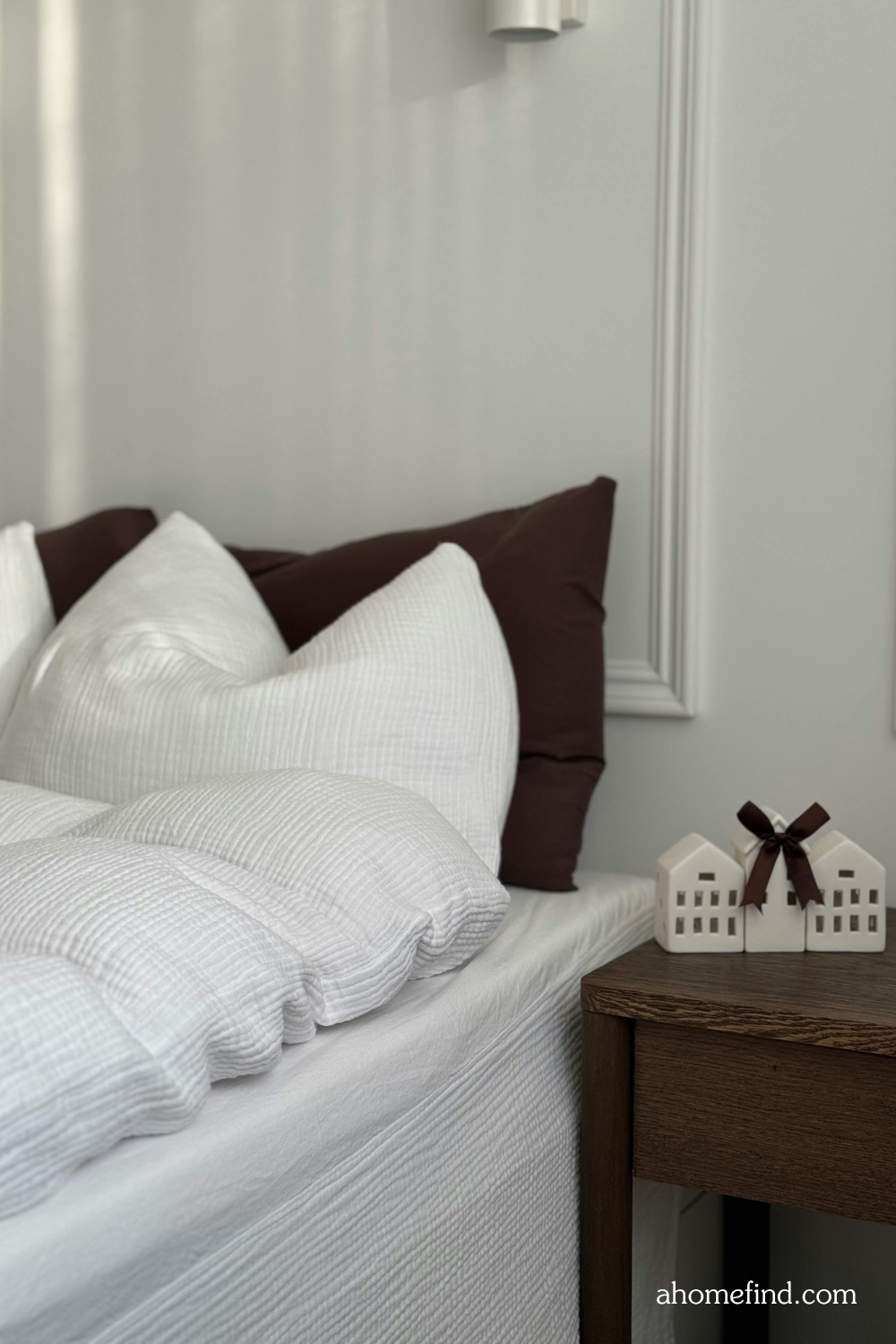 White perfect bed sheets, a wooden night stand and details on the wall. Scaled. 