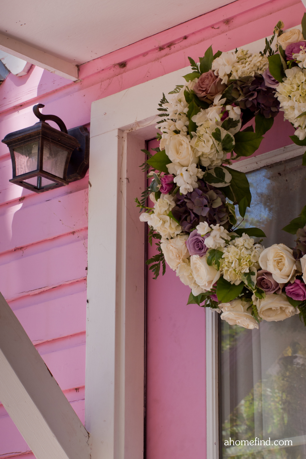 Spring wreath for front door on a pink wall. Front porch decorating ideas for spring.