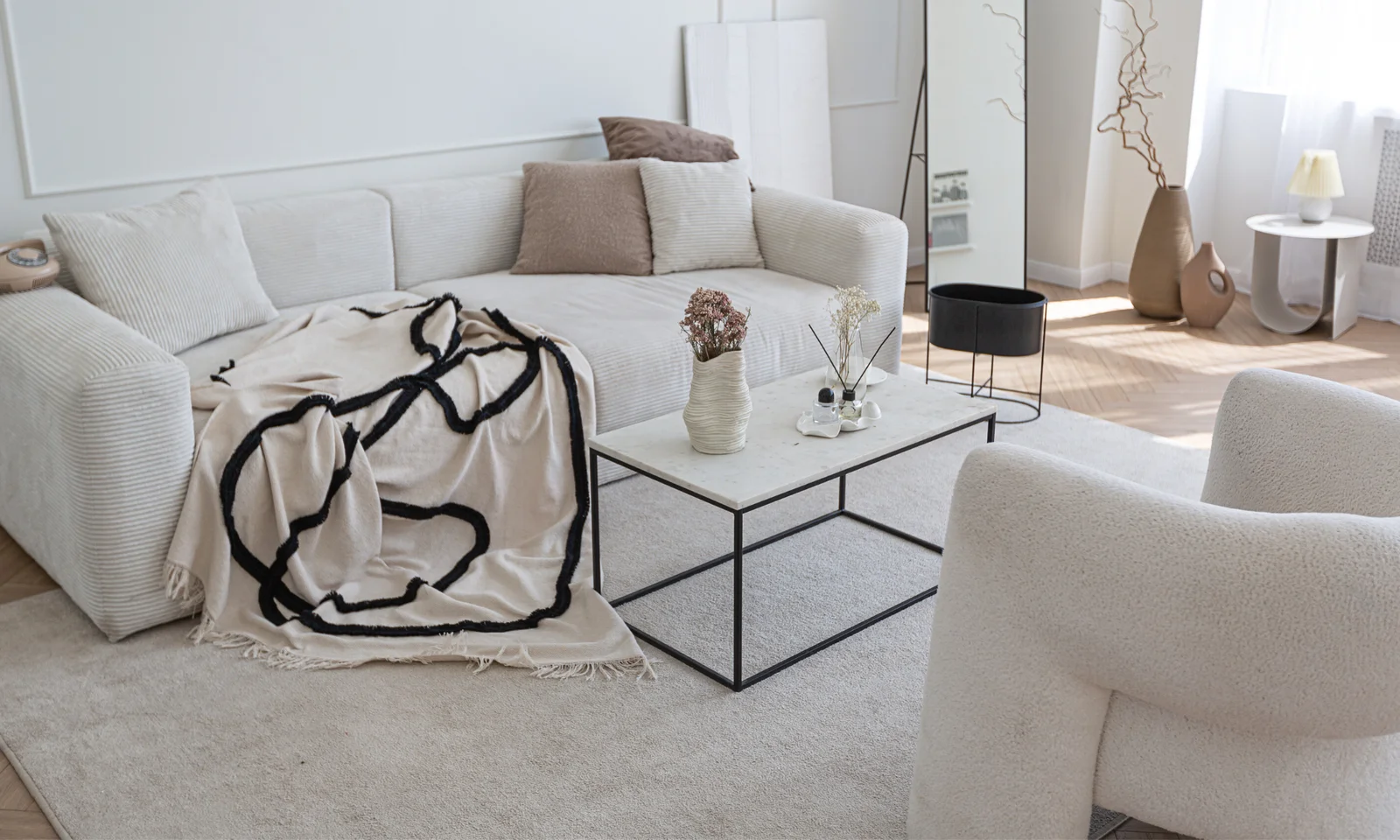 Small apartment interior design with white sofa and a white armchair. A coffee table in the middle.