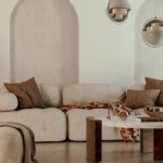 A japandi living room with a beige couch, earthy tones and a coffee table with wooden legs. Hanging ceiling lamps. Scaled.