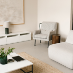 A minimalist living room with two armchairs, a coffee table, a large wall art and decor pieces.