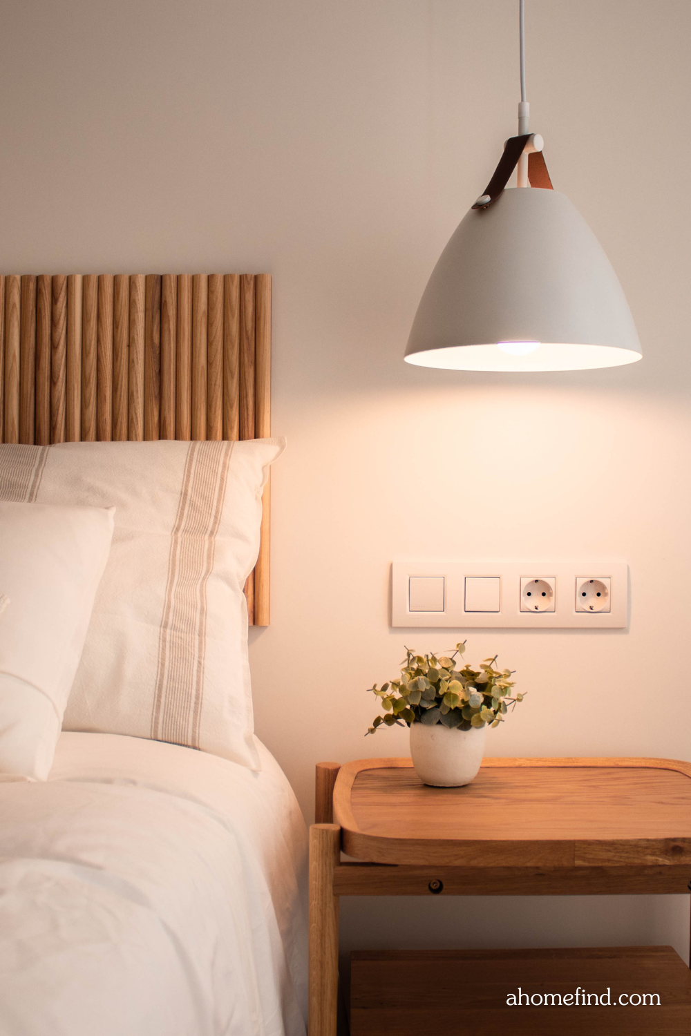 Warm white vs cool white. A ceiling lamp above a bedside table next to a bed.