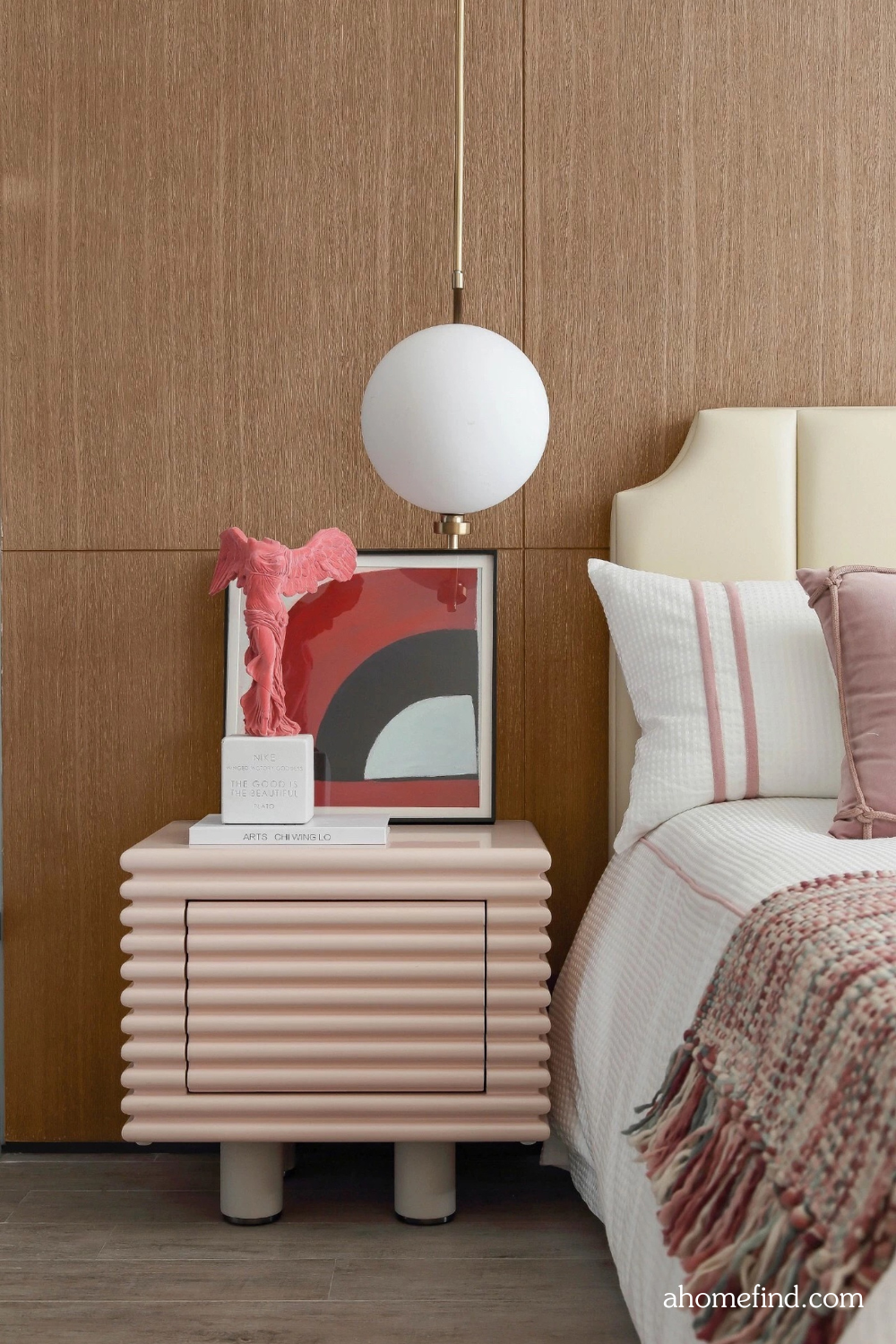 How to arrange furniture in a small bedroom with a large bed. A pink bedside table and pink bedding. A window.