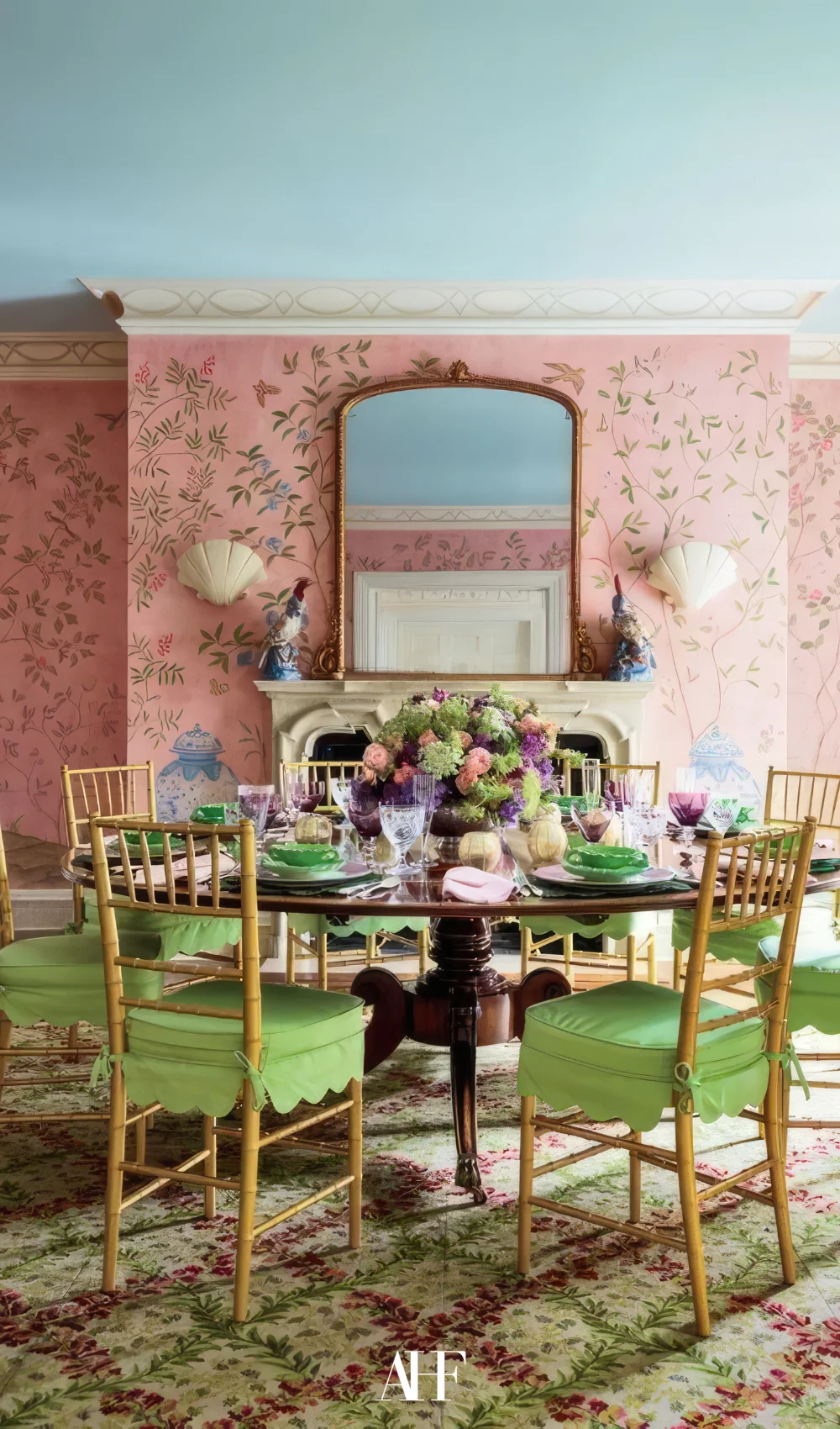 A maximalist dining room with lime green table and chairs. Pink walls and a blue roof. Maximalist interior design.