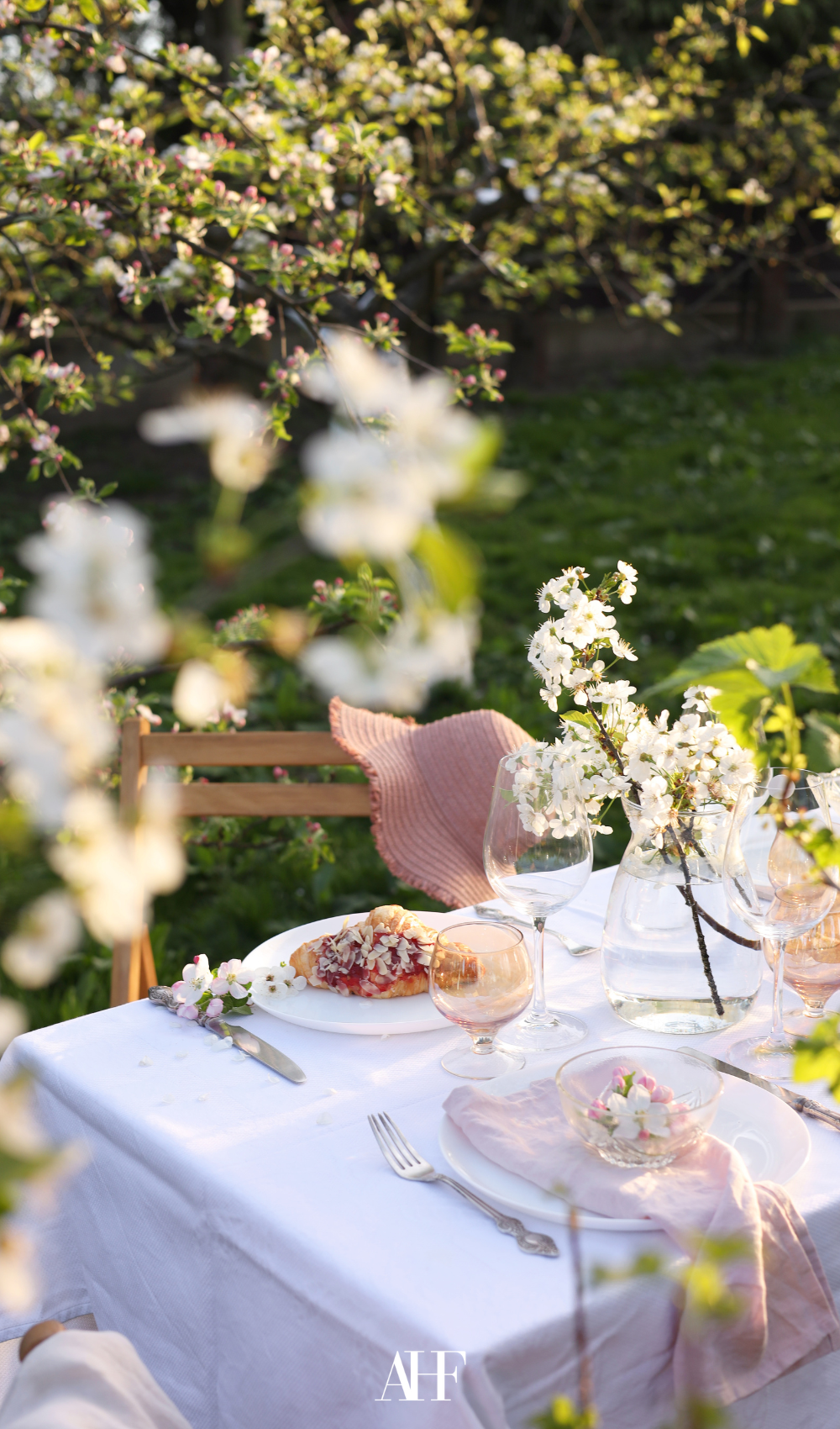 Classic midsummer table setting in the garden with a crisp white tablecloth. Midsummer table decor.