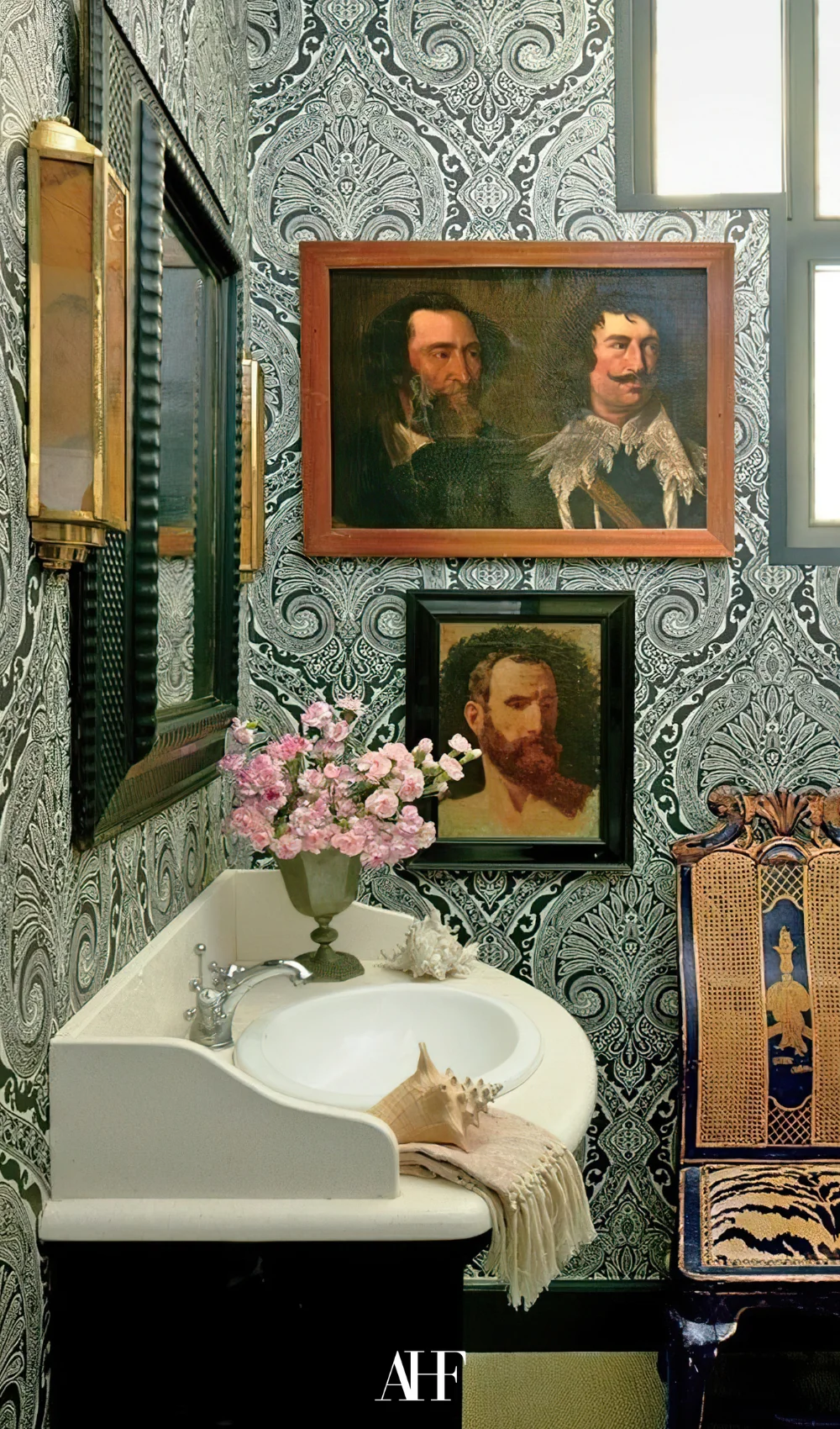 A maximalist bathroom with wall art, a sink and a patterned wallpaper.