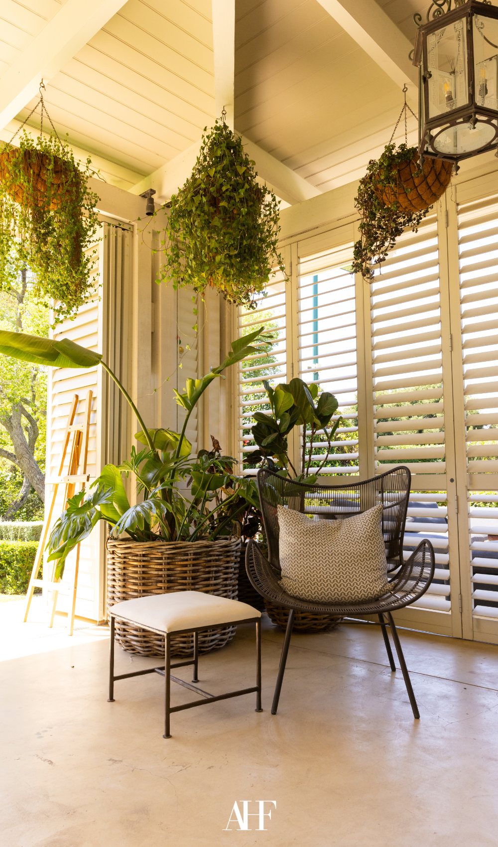Outdoor-indoor feeling with a chair and a stool, lots of plants and a view of the outside.