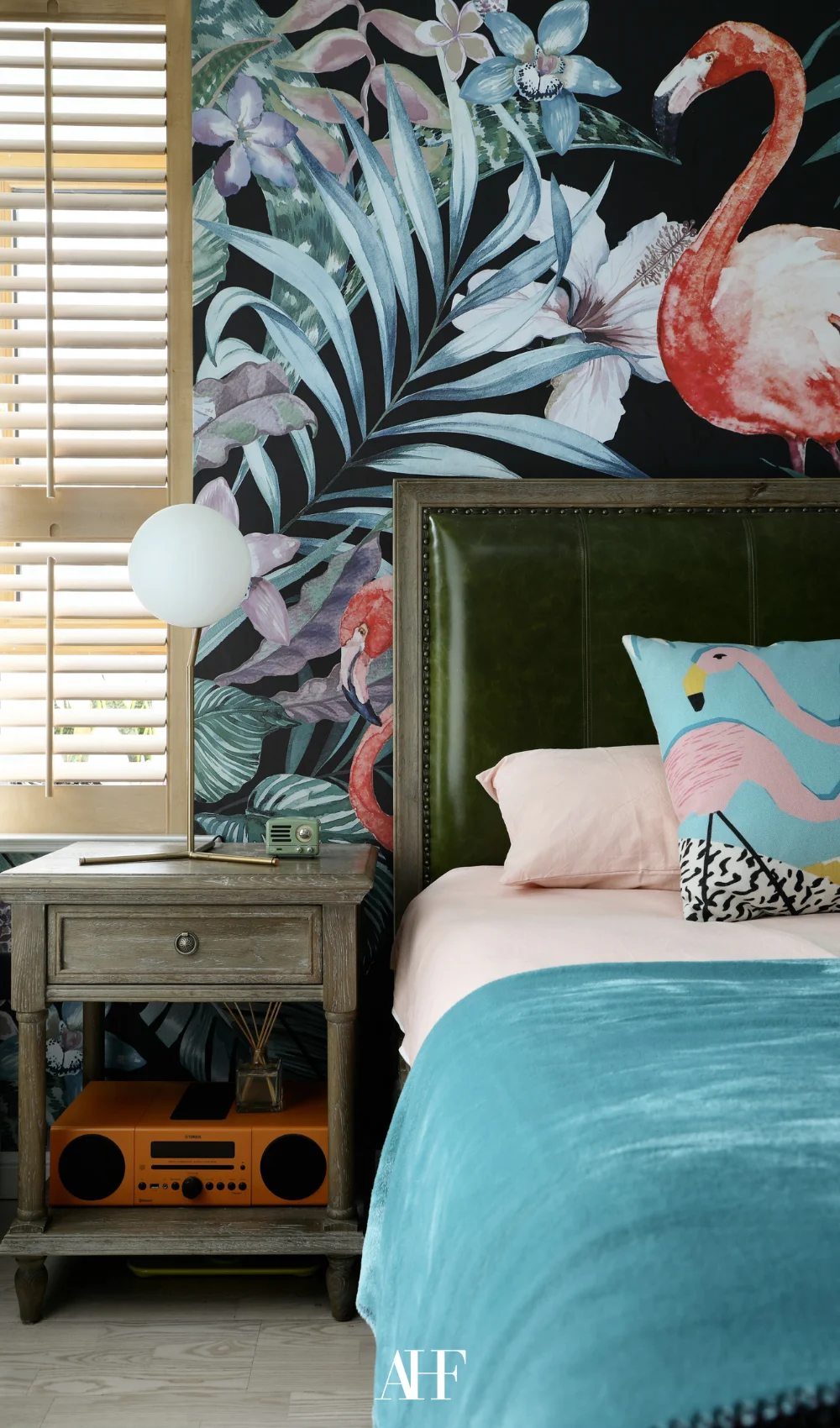 A maximalist interior design bedroom with flamingos on the wall, a large bed and some decorations.